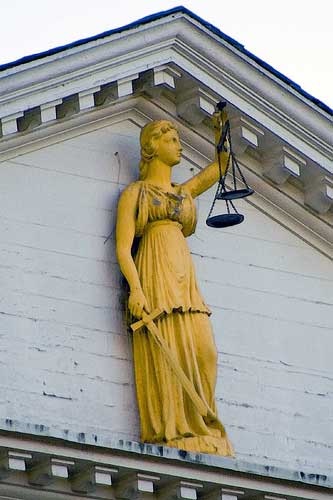 Statue of Justice at the top of the courthouse, holding a scale and sword