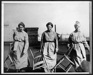 Hopkins with two other suffragists, carring chairs and walking toward the camera