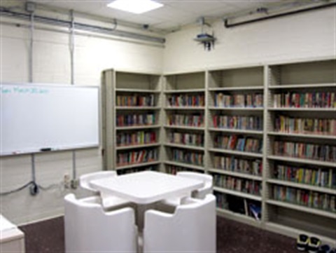Classroom with a table, chairs, whiteboard, and bookshelf