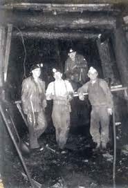 Group of 4 miners underground, posing for the camera