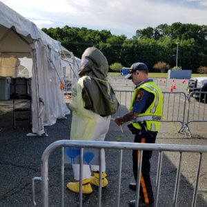 Morris County Sheriff's Officer Stephen Nowatkowski assists a medical technician with securing their personal protective equipment at the Morris County COVID-19 test site on June 26, 2020.