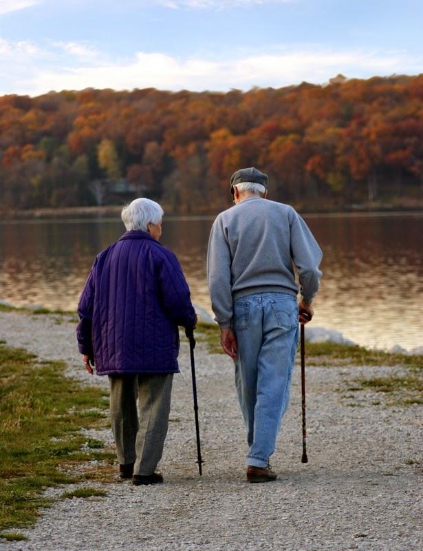 Old couple, man and woman, with canes, walking along a riverfront