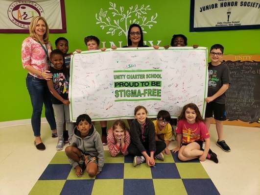Unity students and teachers hold up a banner with the phrase Unity Proud to Be Stigma-Free