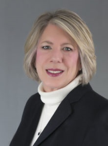Commissioner Smith, wearing a white turtleneck and black blazer.