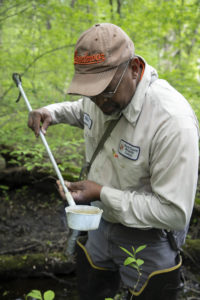 An inspector uses a simple dipper is used to check for mosquito larvae.
