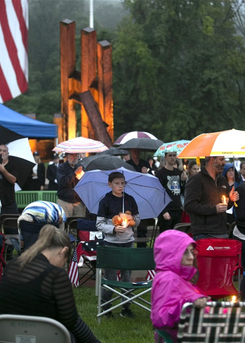 boy with umbrella at 911 ceremony with memorial in background