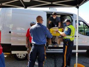Morris County Sheriff's Office Detective Andreas Zaharopoulos, in blue shirt, and Sheriff's Officer Stephen Chiarella, in yellow vest, assist at a food distribution event at County College of Morris on June 23. 