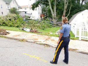 Morris County Sheriff's Officer Dianna Bustamante surveys damage to a tree and power line in Dover as she secures a section of roadway from being traveled after Tropical Storm Isaias.
