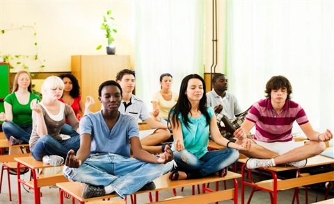 Teens sitting on top of their school desks, meditating