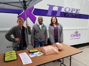 3 members of the HOPE ONE staff, set up in a tent outside of the van