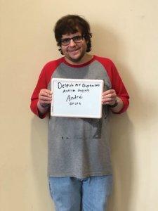 Andres Ortiz holds a sign that says, Despite my Diagnosis, autism success.