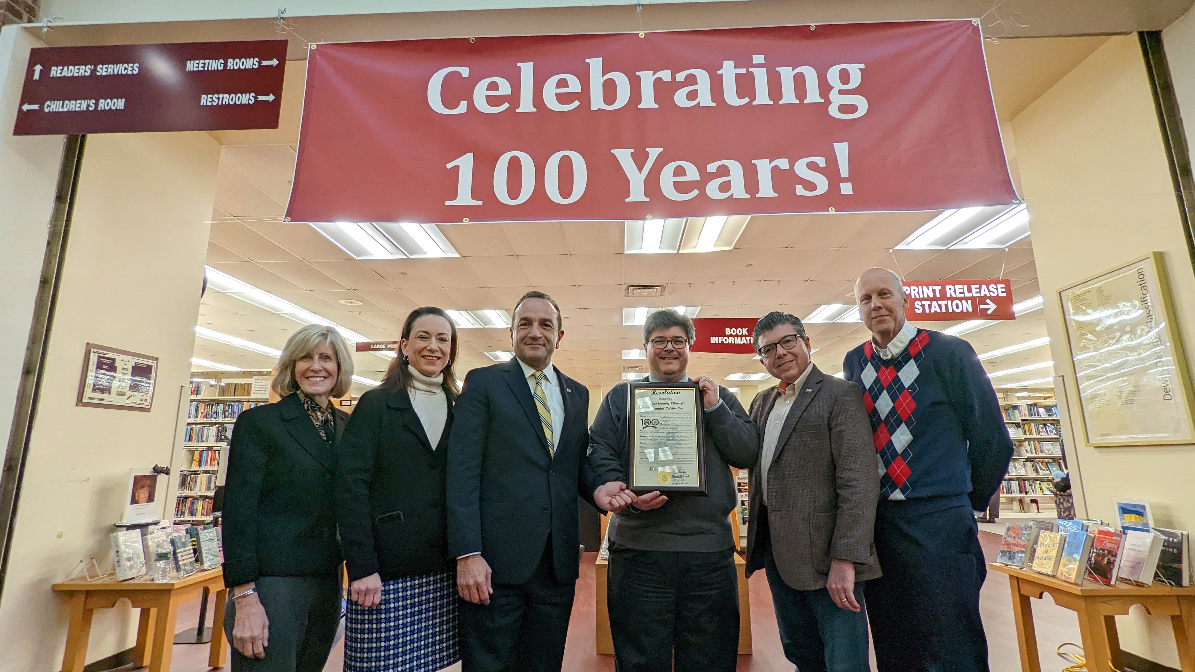 Officials with sign marking 100 years