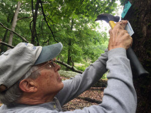 photo of Lake Hopatcong Trail volunteer Keith Schilling nailing a trail blaze on a tree