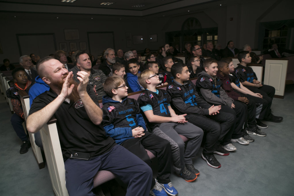 photo shows players and coaches at Freeholders' event watch a film showing their winning touchdown