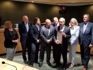 Delta Dental President and CEO Dennis Wilson (holding framed resolution) tells the Board of Freeholders about his company's history and charitable efforts