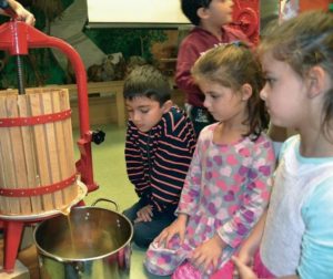Children look at a cider press
