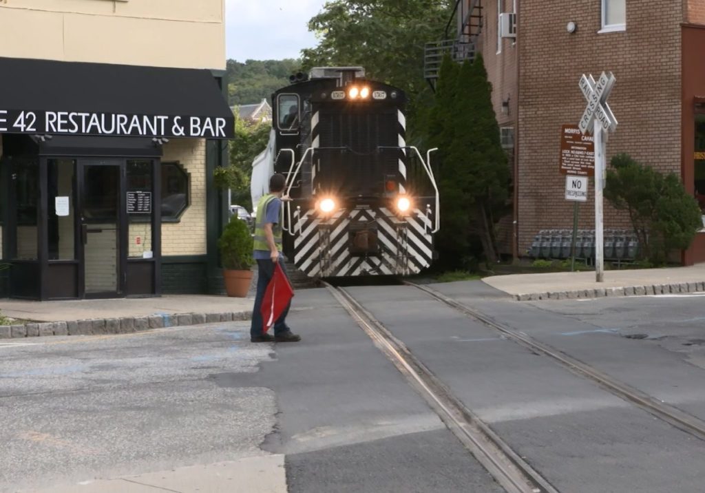 photo shows train coming through tight downtown crossing in Dover between buildings
