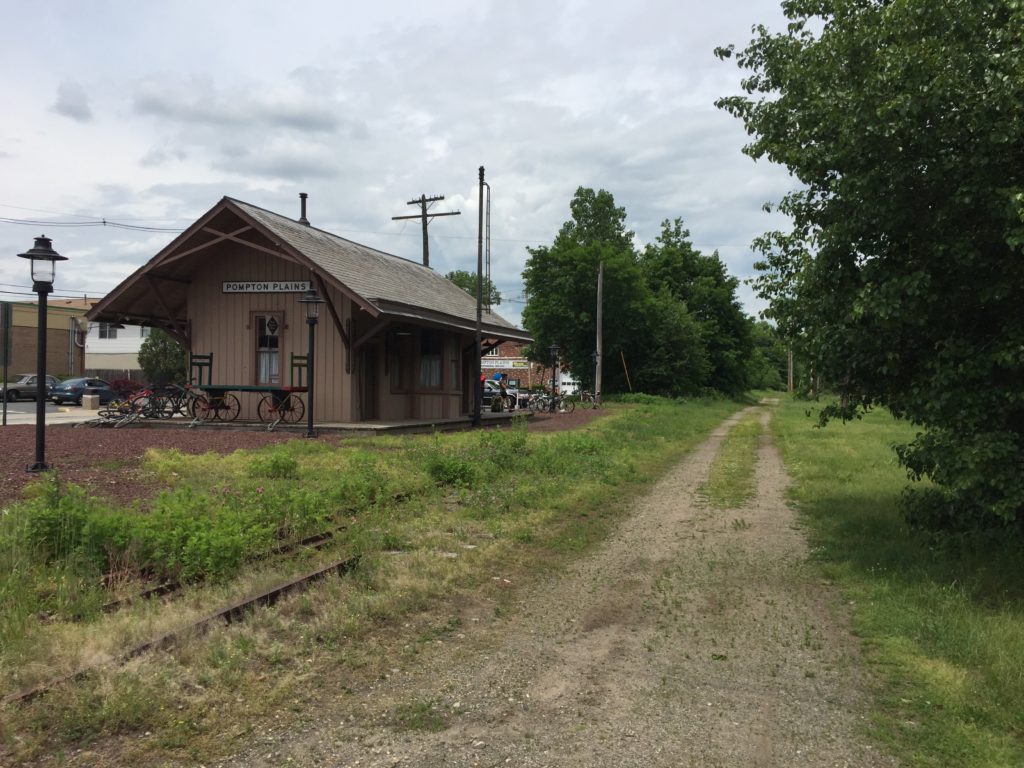 photo shows historic Pompton Plains train station, with abandoned track and path running behind it