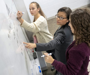students and professor at white board
